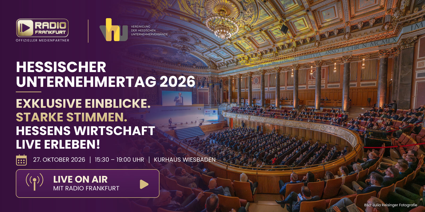 Eine große Anzahl von Teilnehmern sitzt in einem festlichen Saal, während auf der Bühne ein Redner spricht.